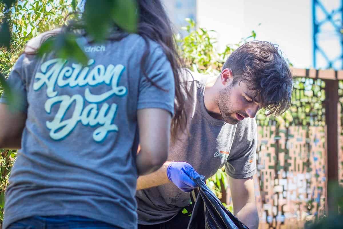 Two Aldrich employees, one man picking up trash and one women with her back facing the camera, during Aldrich's Action Day of community service.