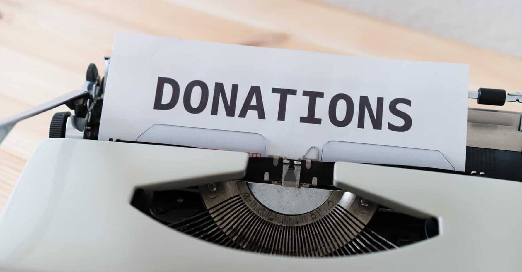 gray typewriter has a piece of paper that has the word, "Donations" typed out on it