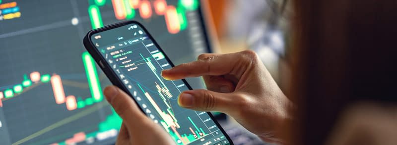 Person looking at stock market on phone and computer