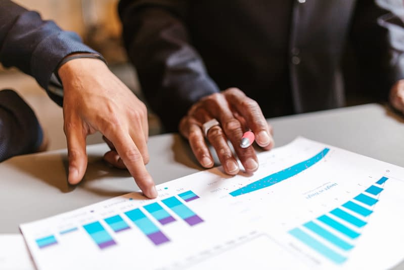 Two people looking at market charts, in which Aldrich Wealth provides market commentary each quarter .