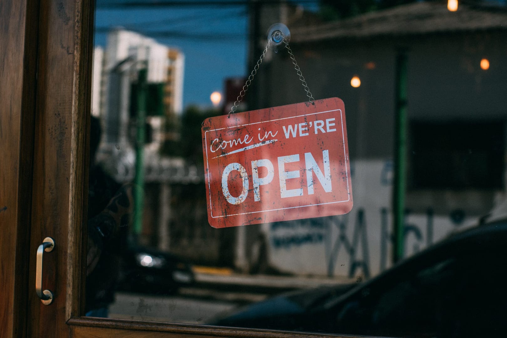 A red sign saying "Come In We're Open" in a restaurant door window during the day. Small minority-owned businesses should be aware of the Restaurant Revitalization Fund (RRF), which would provide them federal funding.