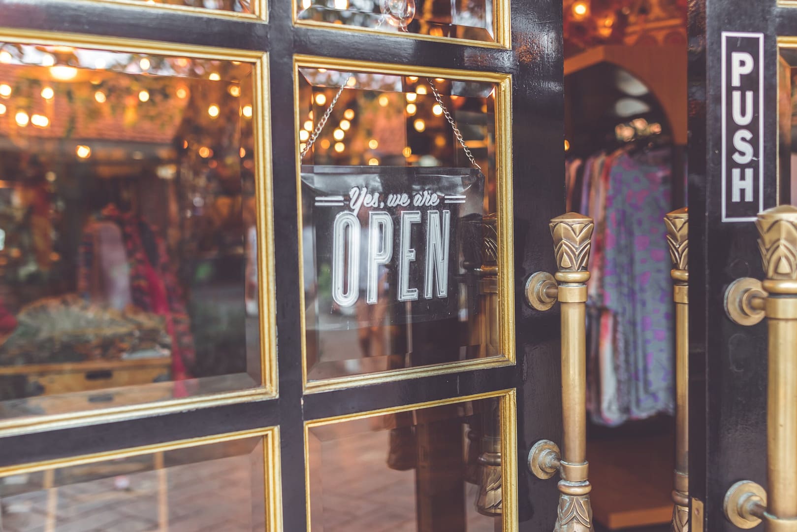 A clothing shop windowed door with the sign, "Yes, we are open."