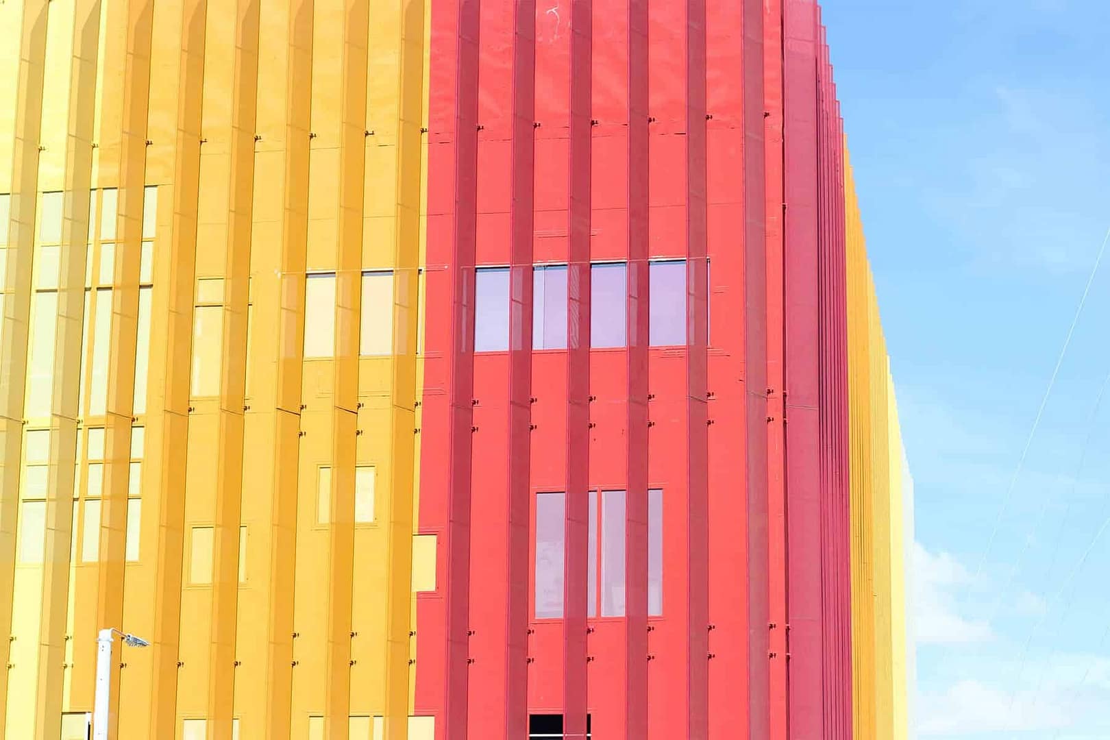 A building that is half yellow and half coral with the blue sky in the background.