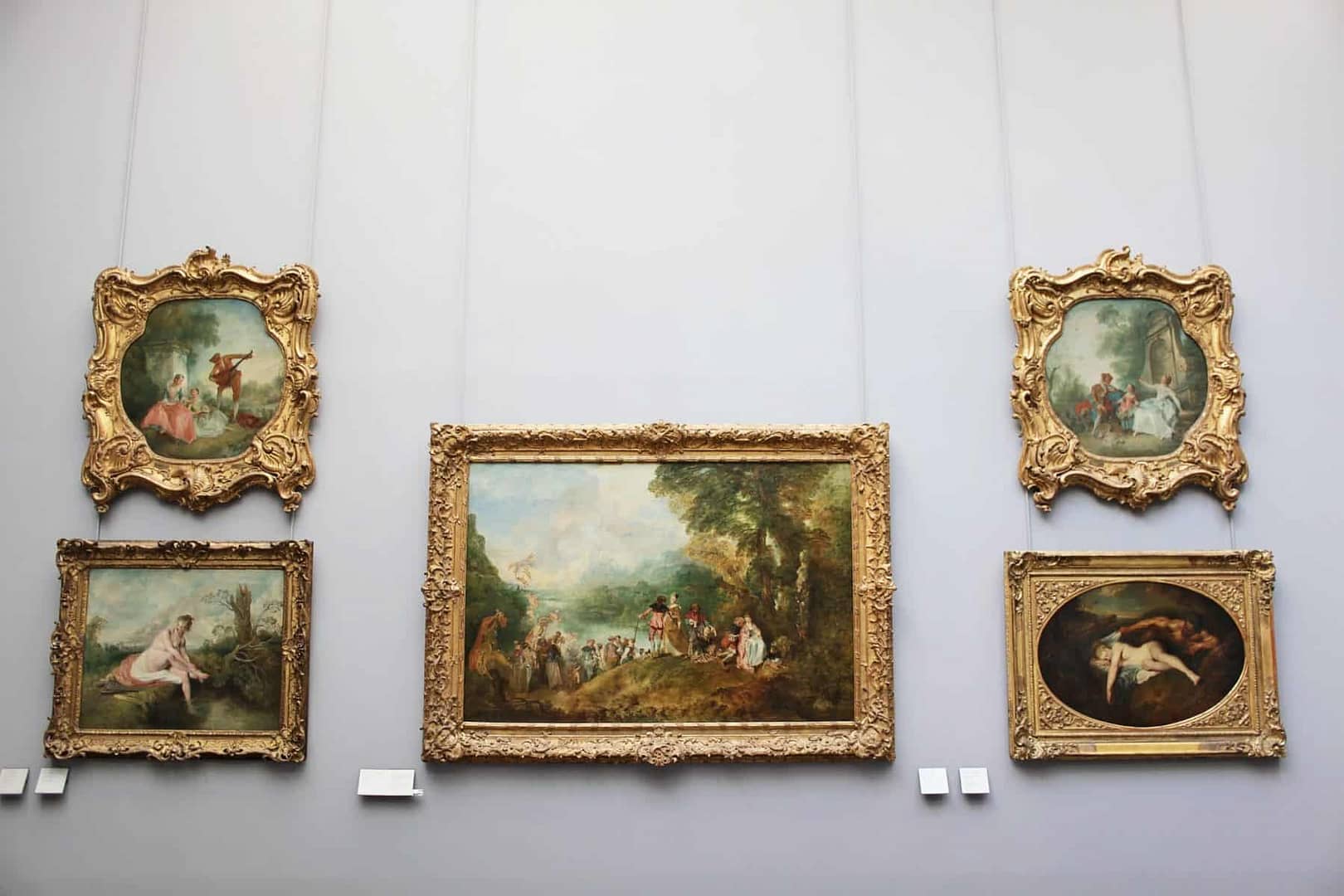 Four art paintings surrounding a larger painting in the center in an art gallery.