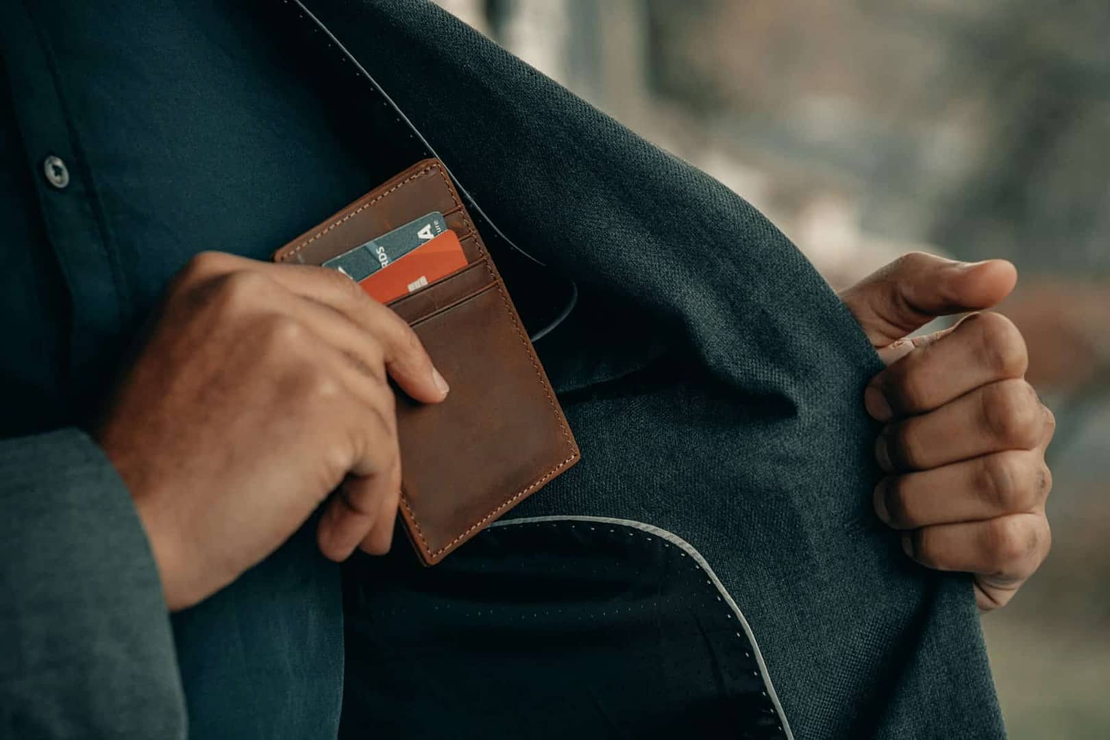 A man tucks his wallet with credit cards inside his jacket pocket