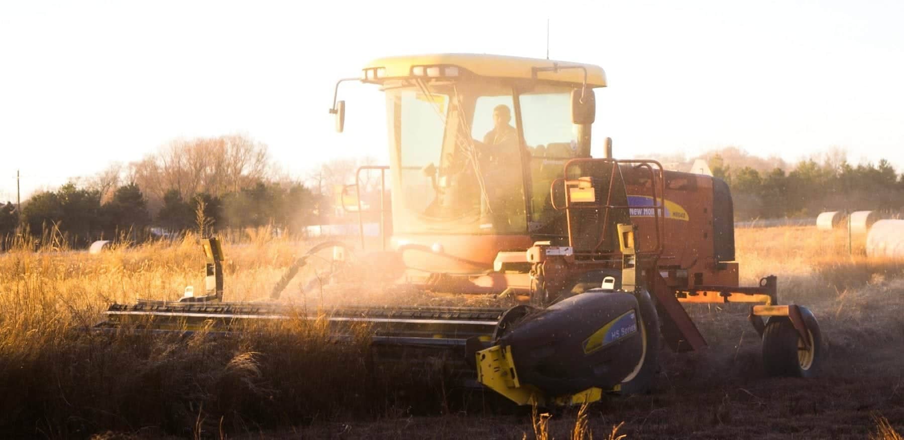 A agriculture tractor with a the sun in the background.