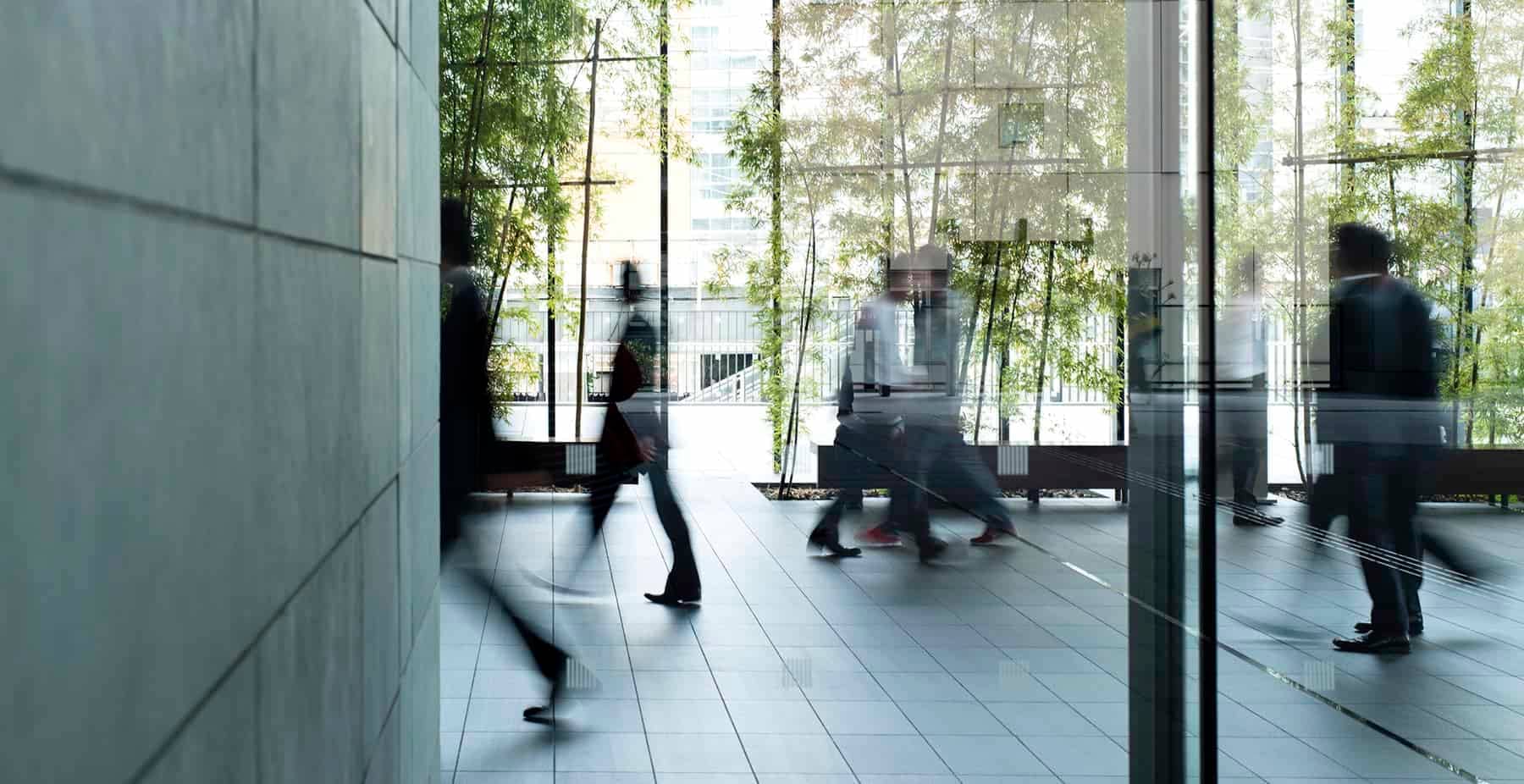 A picture of blurred business figures in an office building lobby.