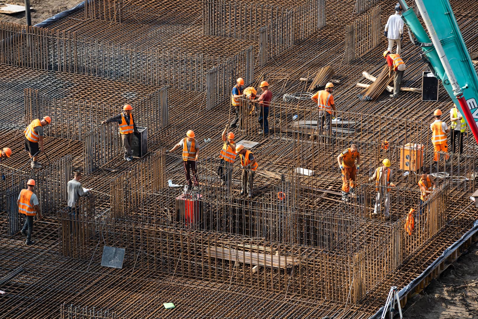 Construction workers in hard hats and safety vests doing concreting work: construction site worker during concrete pouring into formwork at building area with skip.