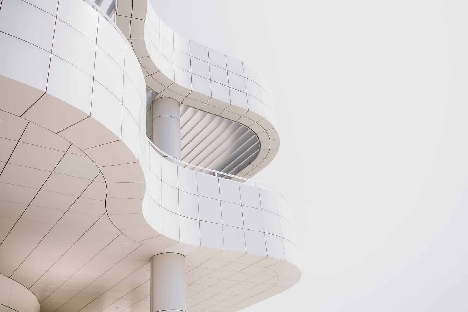 An image of a wavy white-tiled building on an overcast day.