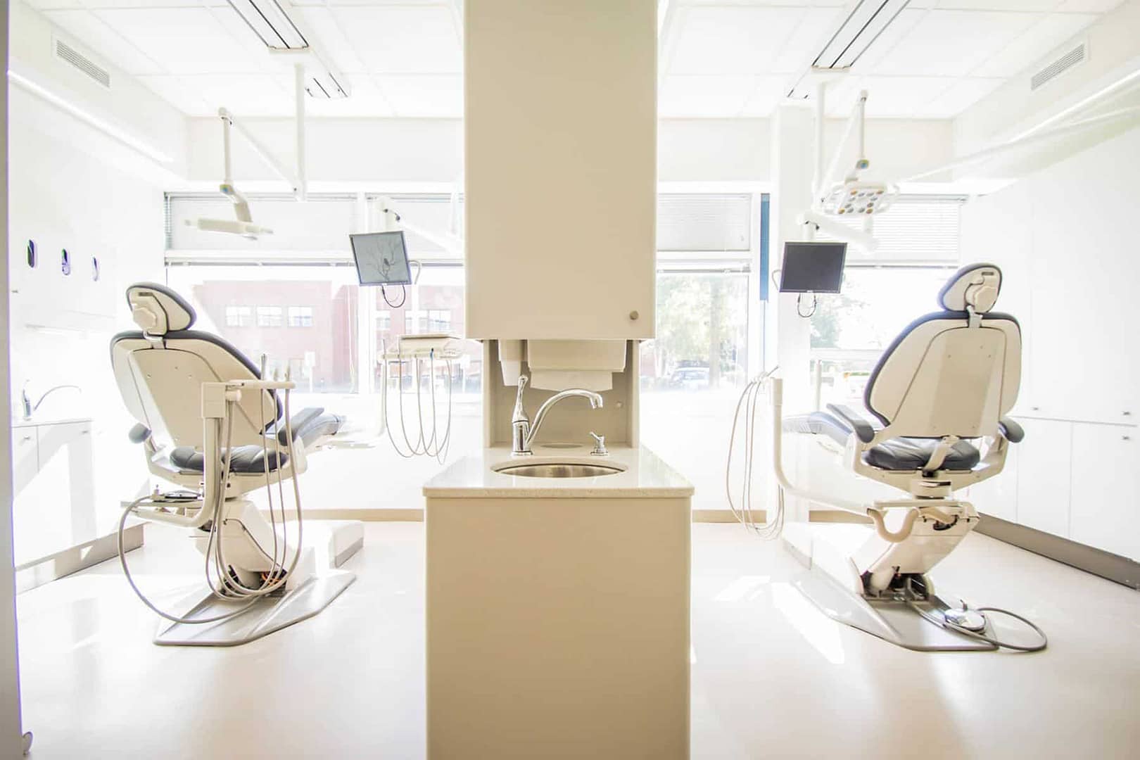 Two empty dental procedure chairs in a dental office.