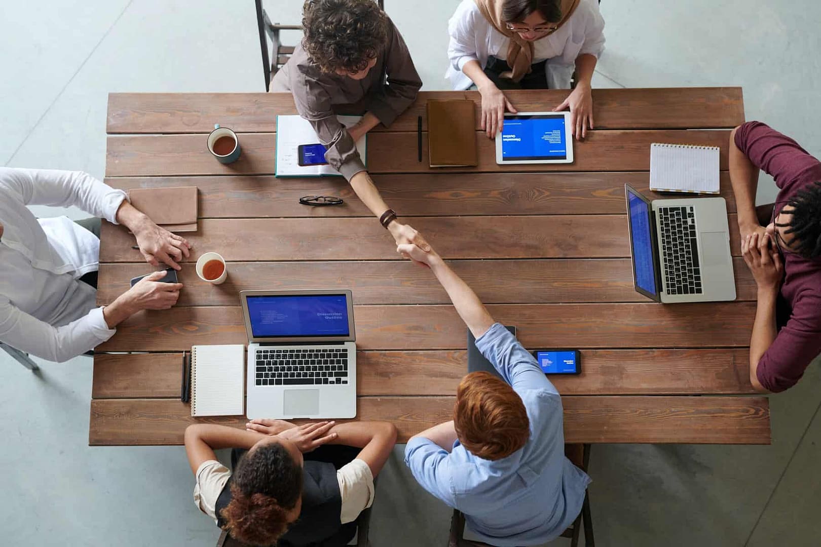 Construction business owners sit at a table with their laptops to discuss liquidating the business