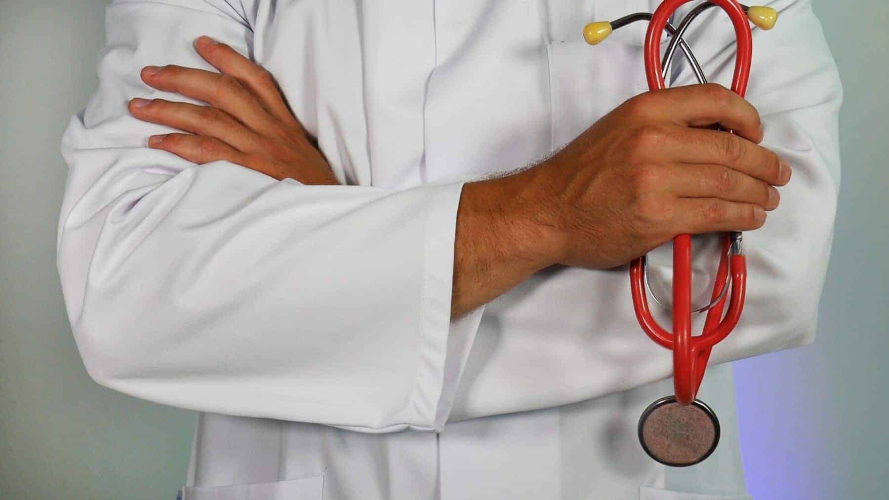 A veterinarian with their arms crossed and a stethoscope in their hand.