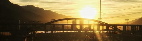 Sunset view of a railroad in an industrial area with a bridge off in the distance