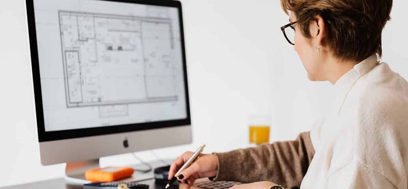 image of an architect at her computer with floorplans