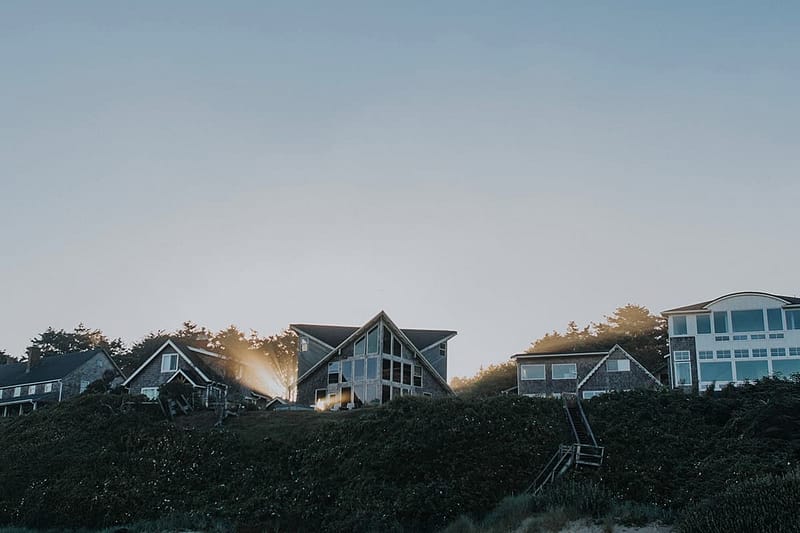 Four houses on a hill with the sun in the background.