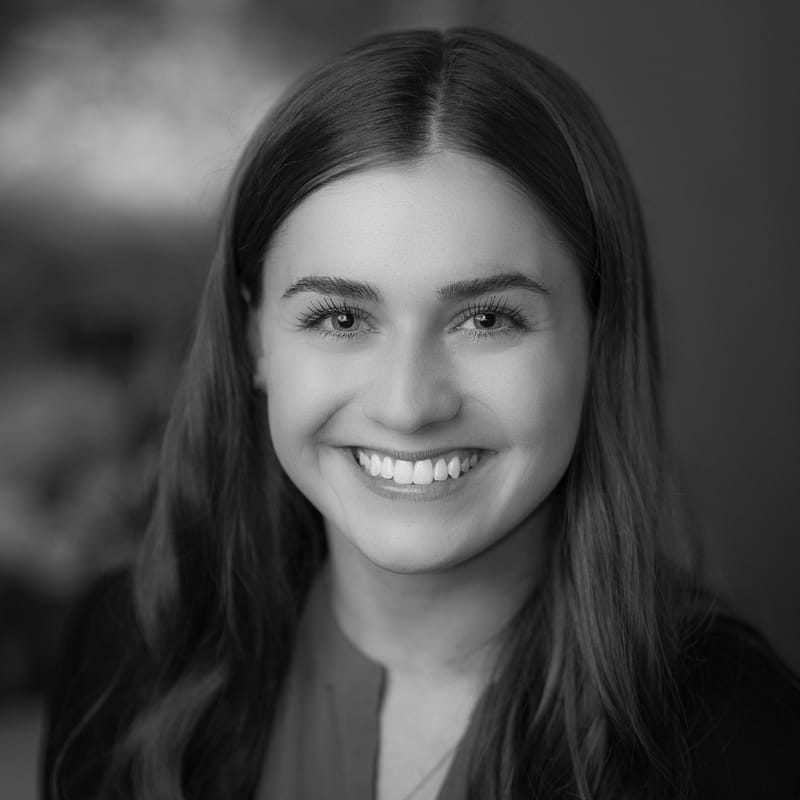Makenna Thies's headshot in black and white in office space.