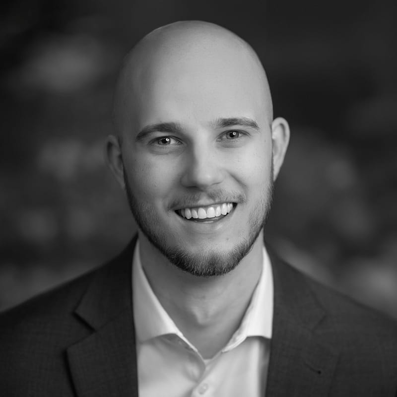 Xander Sinur's headshot in black and white in office space.