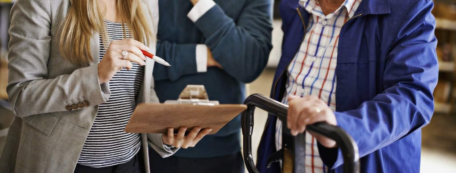 Three people discussing something that is on a clipboard.