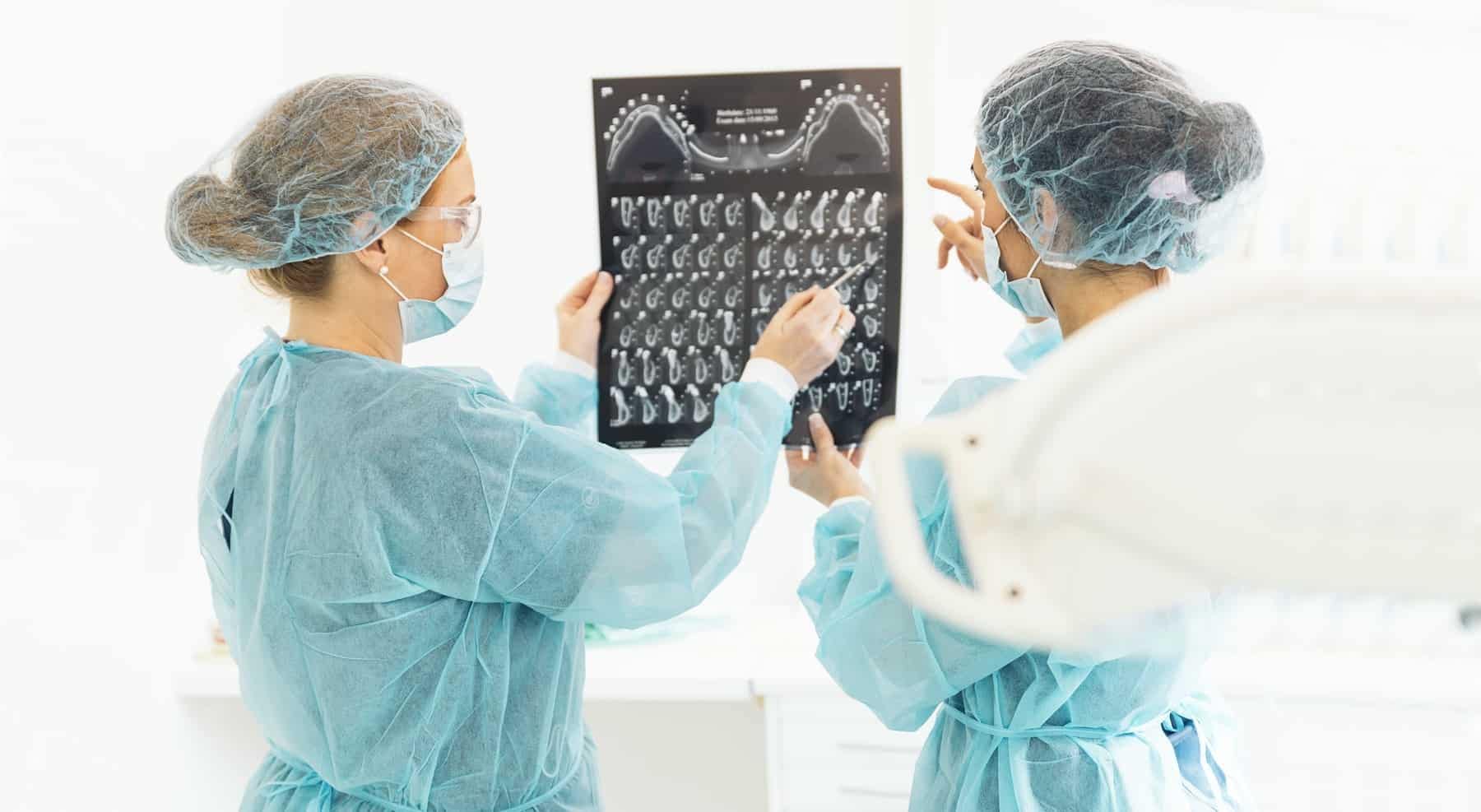 Two dentists in PPE looking at dental x-rays in dental office.