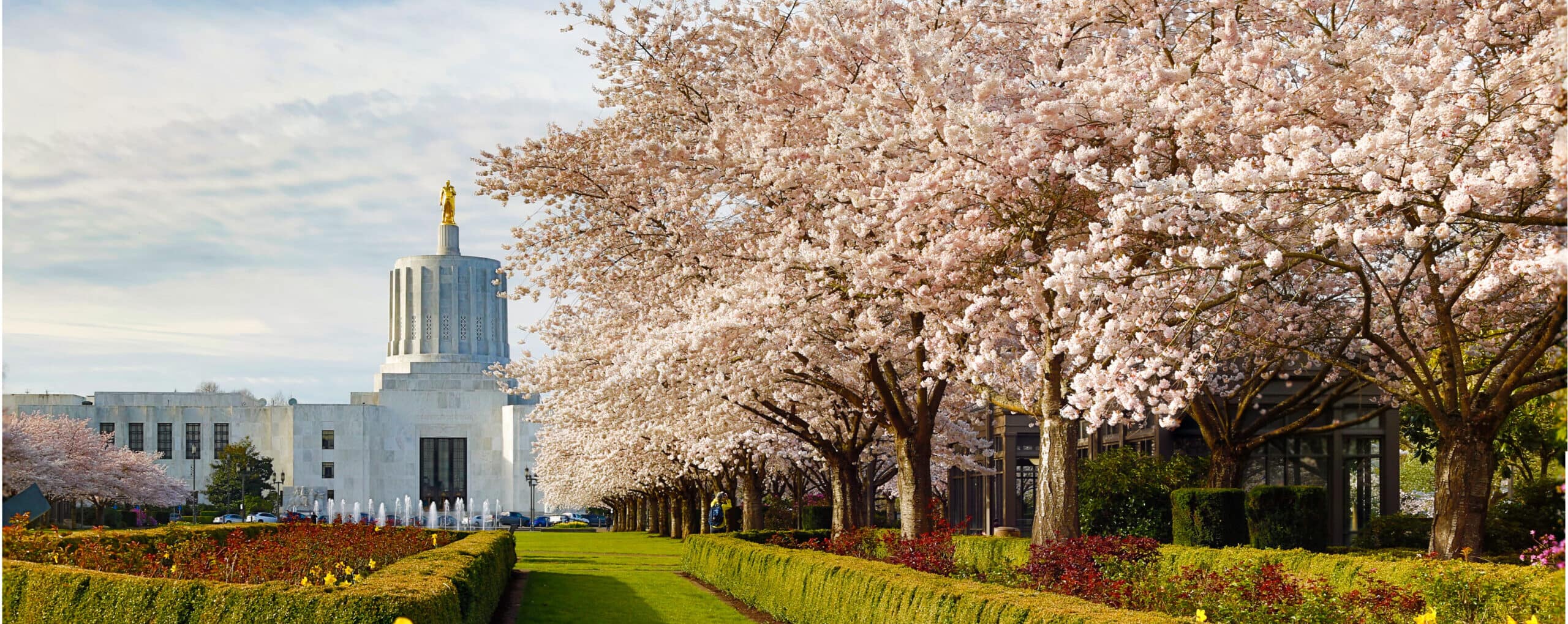 The Oregon state capitol building with daffodils and cherry blossoms in foreground, where Aldrich, which provides tax, audit, accounting, and business consulting services, was named one of Oregon Business Magazine's 100 Best COpmanies to Work for in Oregon.