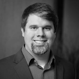 Sam Buck's headshot in black and white in office space.