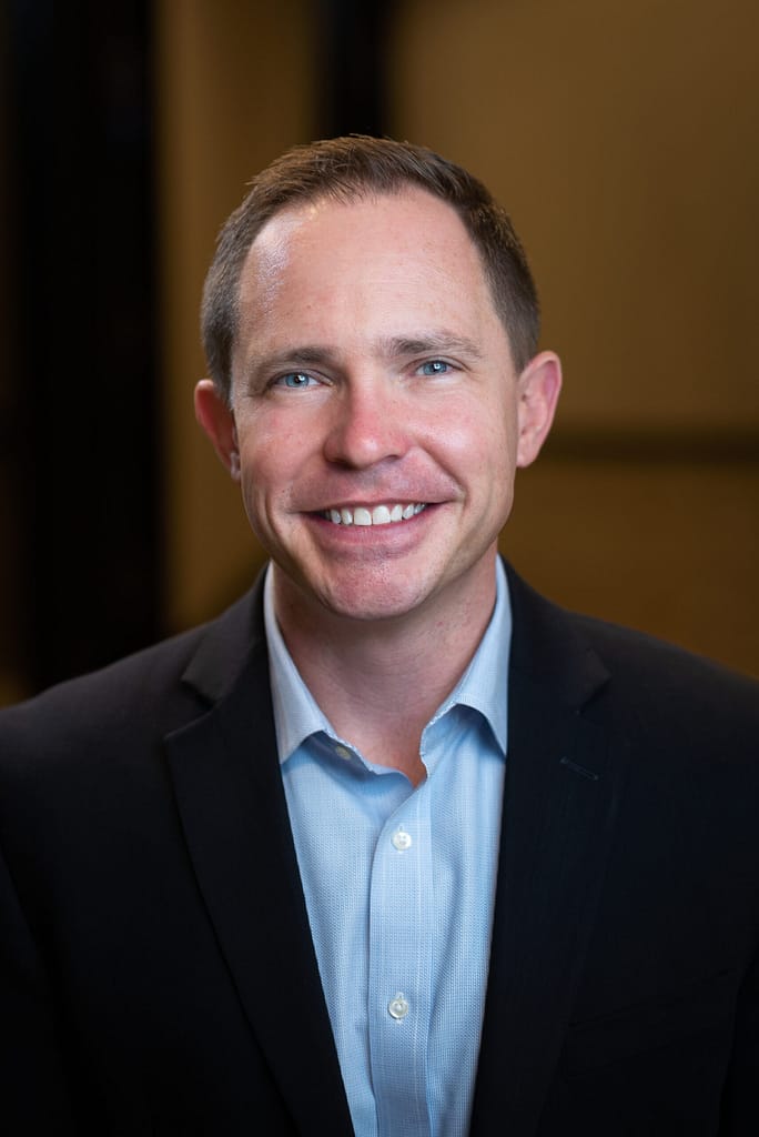 John Lauseng's headshot in full color in office space.