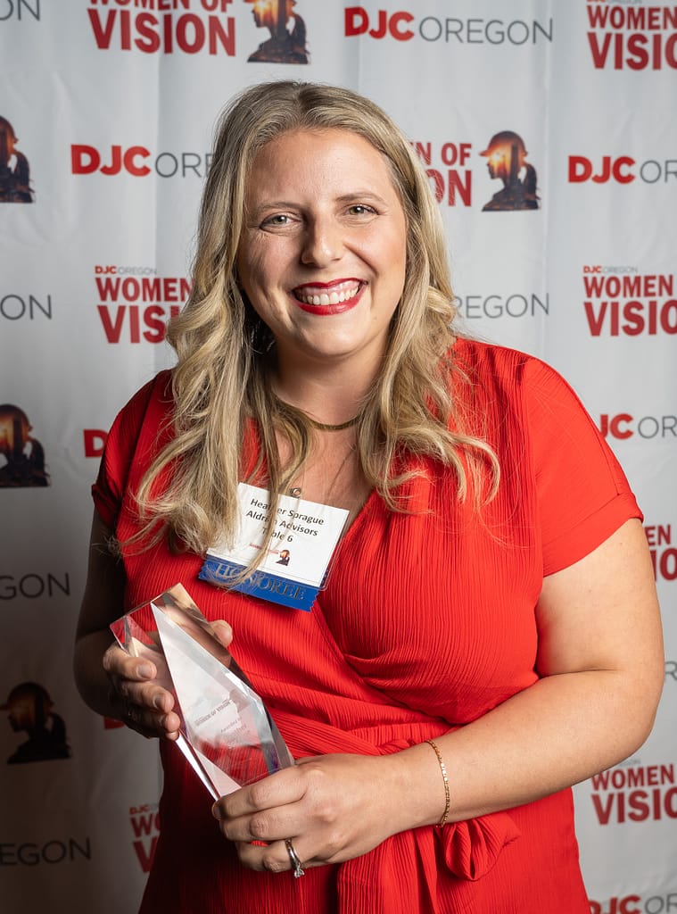 Heather Sprague wearing a red dress and holding her 2025 DJC Women of Vision Award at the ceremony.