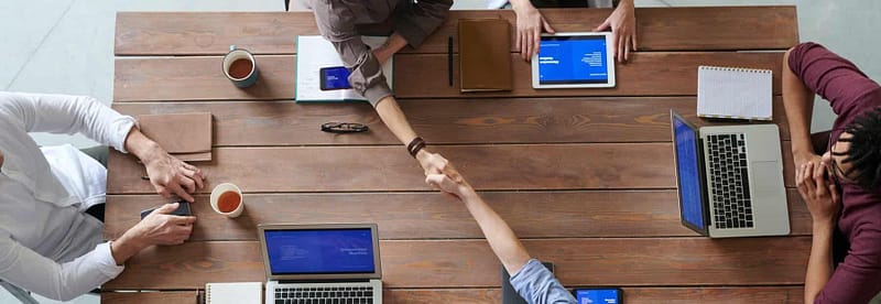 Construction business owners sit at a table with their laptops to discuss liquidating the business