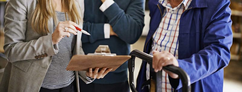 Three people discussing something that is on a clipboard.