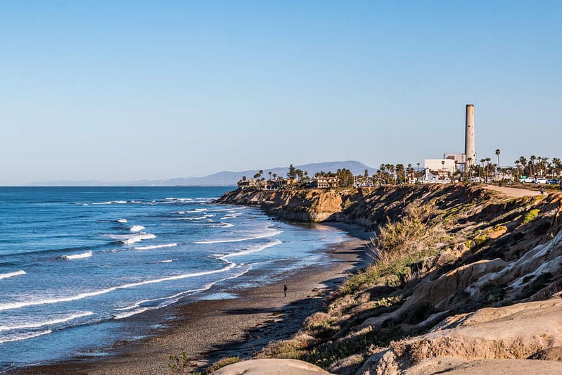 Near cliffs on South Carlsbad State Beach in San Diego, California with the power plant landmark tower in the background.