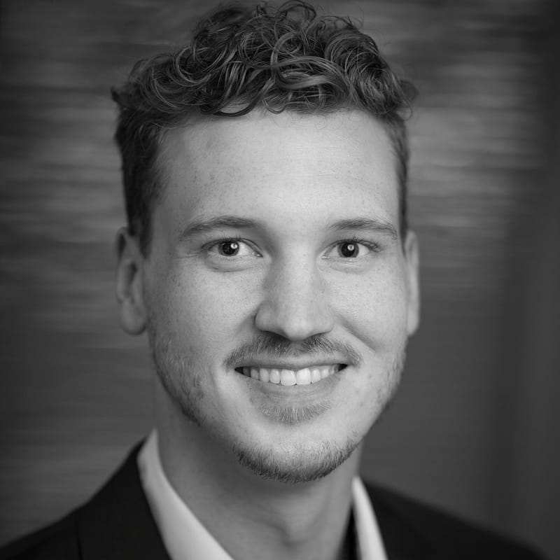 Cyrus Ward's headshot in black and white in office space.