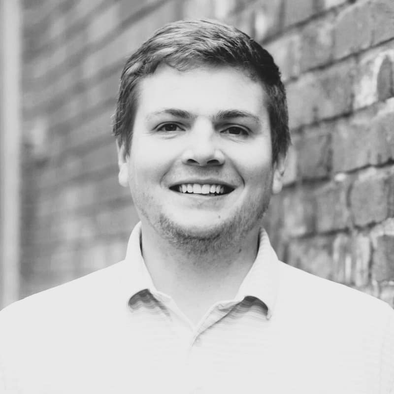 Camden Dayton's headshot in black and white in front of a brick background.