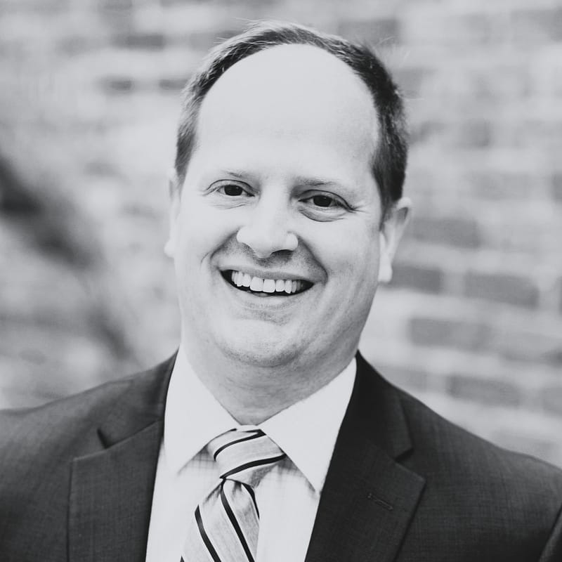 Mike Whitmore's headshot in black and white in front of a brick building.