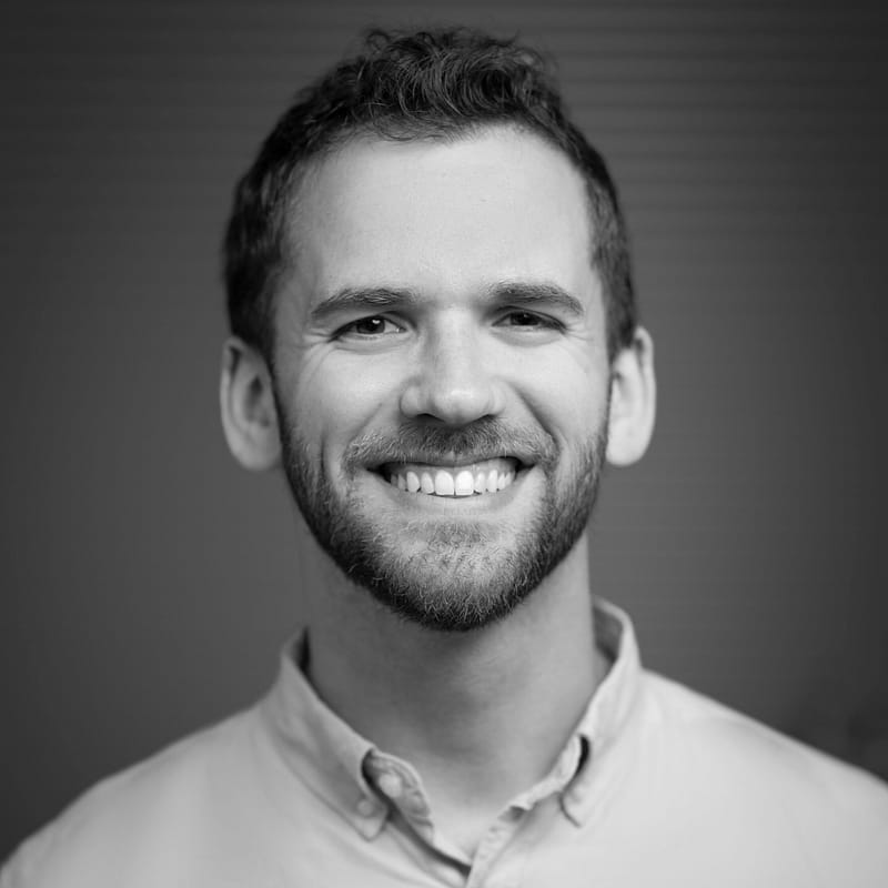 Alexander Green's headshot in black and white in office space.