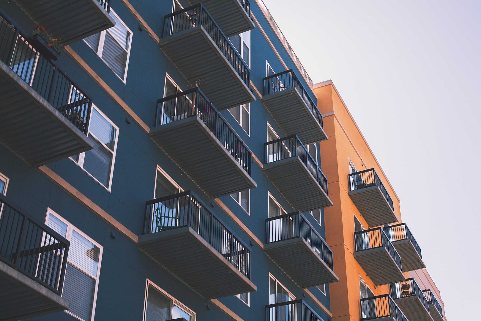 Real Estate, blue and orange apartment buildings with porches on a cloud day