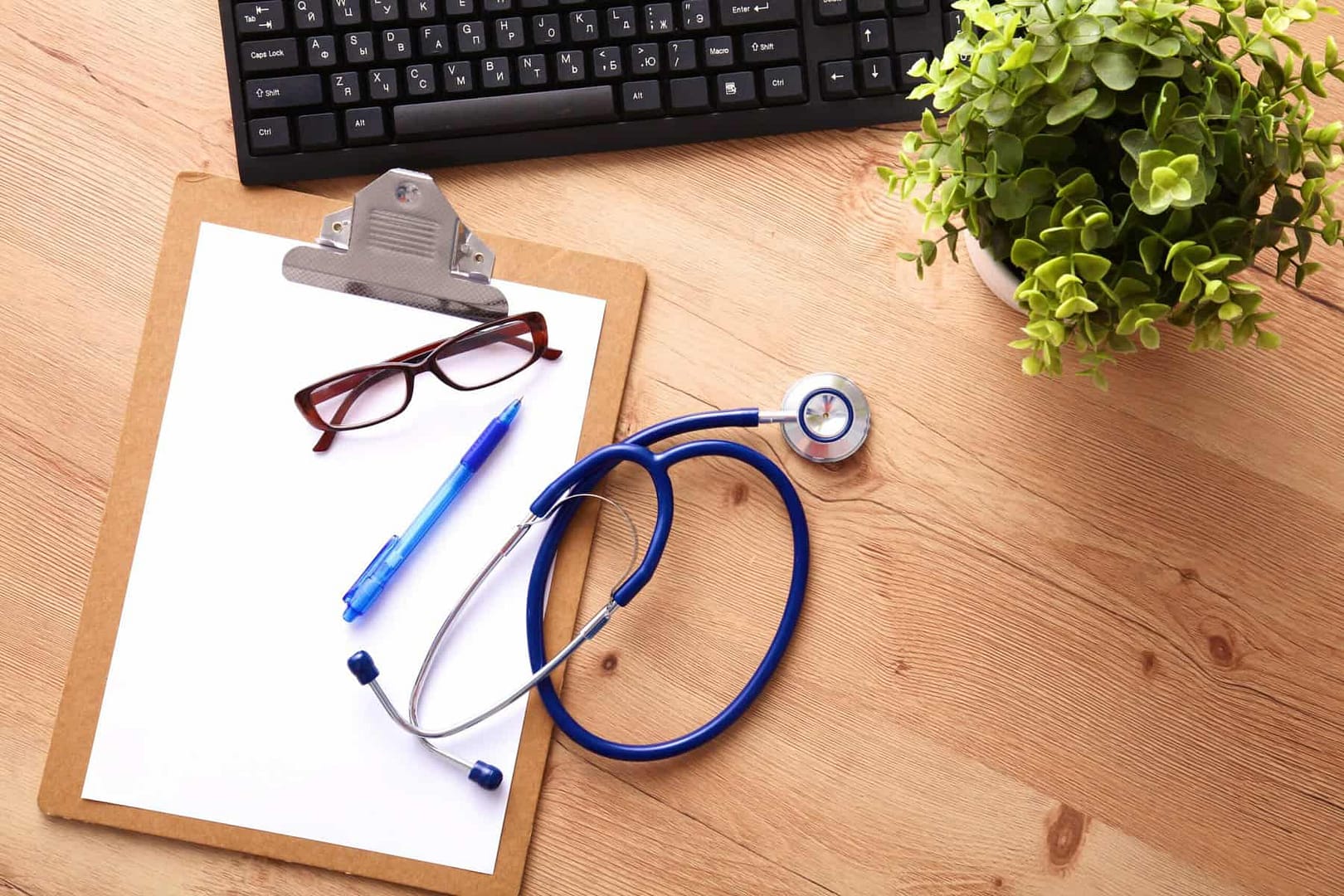 A medical stethoscope near a laptop on a wooden table, on white