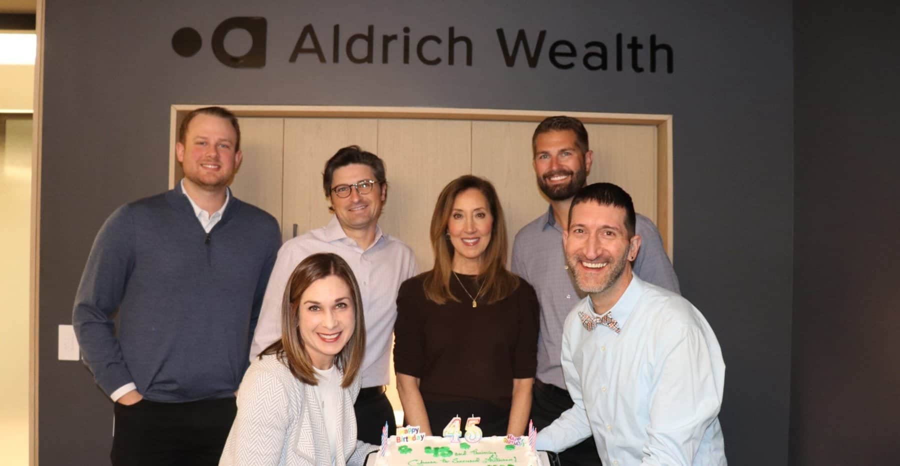 Aldrich Wealth Corporate Retirement Plan Team Group Photo holding a cake in Aldrich Wealth office in Lake Owego Oregon