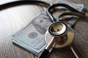 Stethoscope and money on wooden table. Healthcare, medical treatment cost and medicine concept.