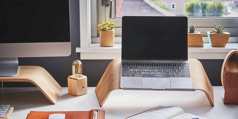 home office desk with two computers and a mouse and notepad